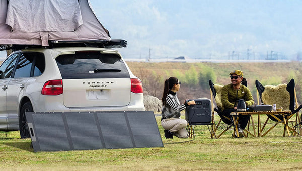 Couple camping beside SUV with BLUETTI power station and panels